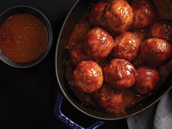 Pot of hamballs covered in sauce and served with a side of sauce