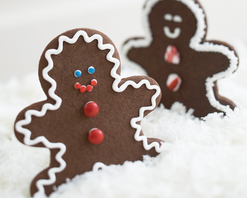 Two decorated ginger bread men on top of coconut flakes