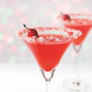 Coconut and sugar-rimmed martini glass filled with Christmas Cosmo, garnished with cranberries