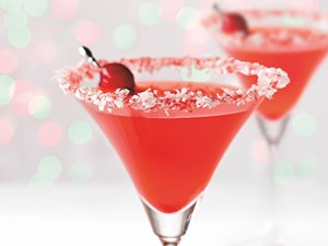 Coconut and sugar-rimmed martini glass filled with Christmas Cosmo, garnished with cranberries