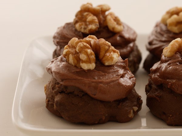 Plate of chocolate drop cookies topped with chocolate icing and walnuts