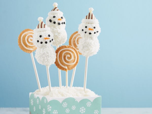 Cake pops covered in white chocolate and coconut and decorated as snowman with candy and frosting