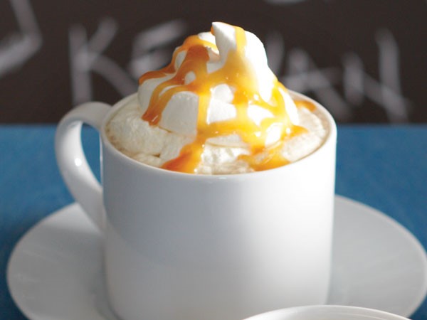 Mug of candy bar latte topped with whipped cream and caramel drizzle