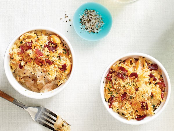 Two small white bowls of cauliflower white cheddar mac and cheese next to small blue dish of salt and pepper