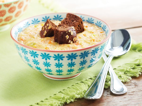 Blue-patterned bowl filled with cauliflower soup and topped with pumpernickel bread cubes