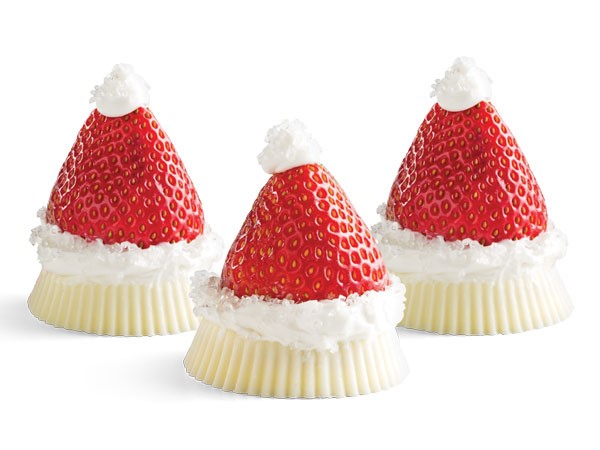 Upside-down white chocolate peanut butter cups topped with layer of white frosting and a destemmed whole strawberry with a dollop of white frosting at the top