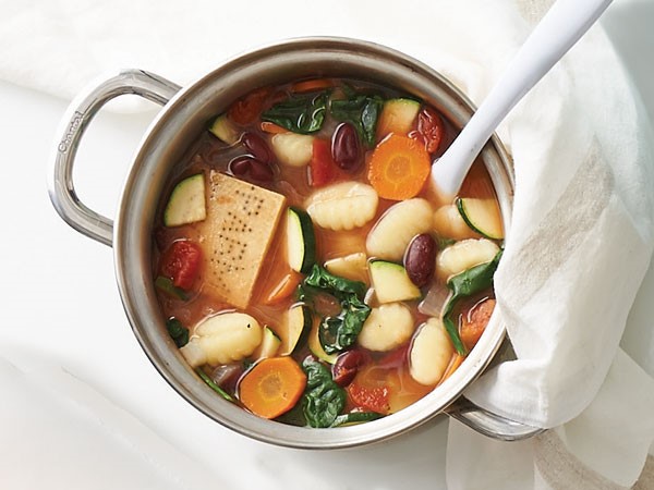 Pot of soup filled with gnocchi, vegetables and parmesan cheese