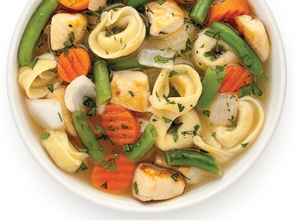 Bowl of tortellini soup mixed with carrots, onions and green beans