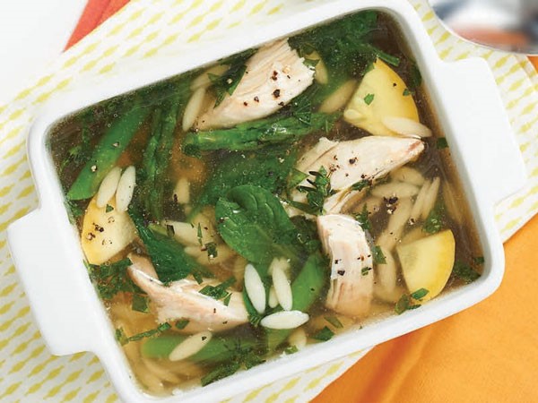 Pan of soup filled with orzo, squash, chicken, spinach and asparagus