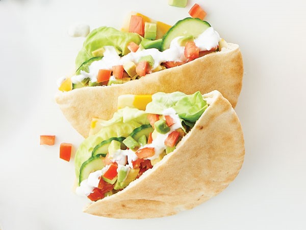 Two pita pockets filled with ranch-seasoned Greek yogurt, cheese, lettuce, avocado, tomato and cucumber