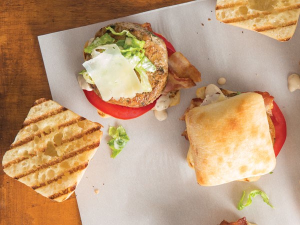 Grilled ciabatta rolls topped with chicken patty, lettuce, tomatoes, bacon and mozzarella shavings