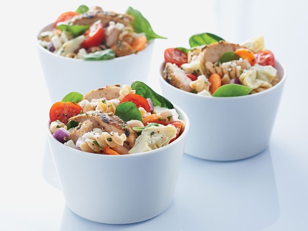 Small white bowls of chicken pasta salad with basil