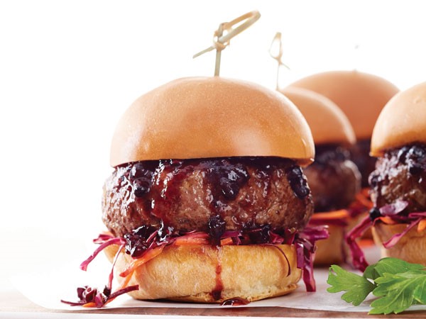 Burger patty topped with blackberry-bourbon sauce with slaw between a toasted slider bun