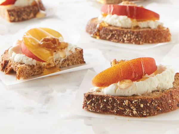 Bread topped with goat cheese, peach slices, honey, and walnuts