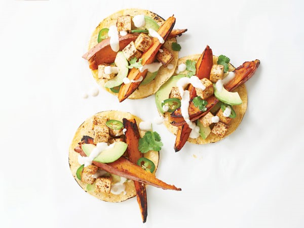 Corn tortillas filled with sweet potato wedges, tofu and avocado and topped with lime cream sauce, cilantro and jalapeno