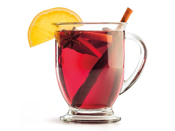 Glass of mulled wine, garnished with cinnamon sticks, star anise and lemon slices
