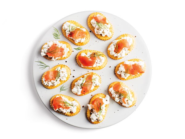 Platter of oval crackers topped with cottage cheese, smoked salmon and sprigs of fennel