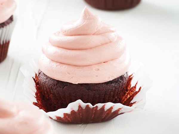 Muffin tin filled with a chocolate beet cupcake and topped with pink butter frosting