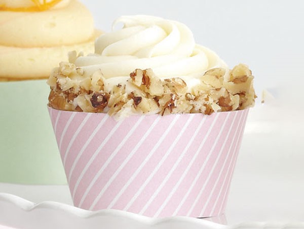 Carrot-walnut cupcake garnished with crushed walnuts in a pink muffin liner