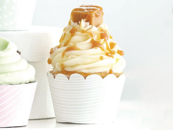 Vanilla cupcake topped with buttercream frosting, a caramel square and drizzled caramel sauce
