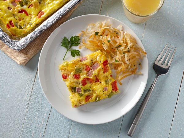 Square-shaped omelet served on a white plate with a side of hashbrowns and a fork