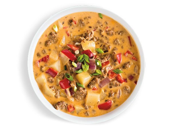 Bowl of cheeseburger chowder garnished with green onions and red bell peppers