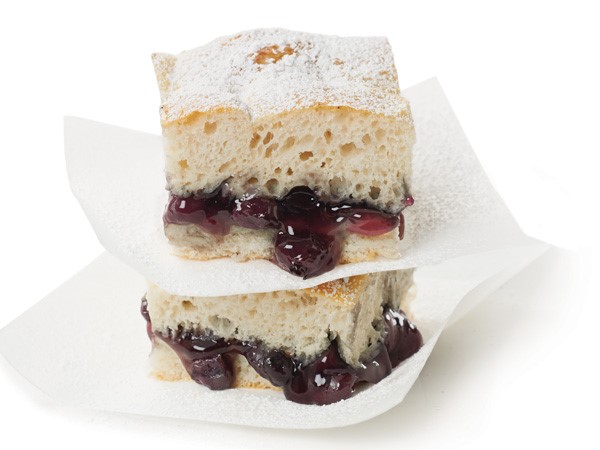 Stack of blueberry cobbler bars between layers of parchment paper