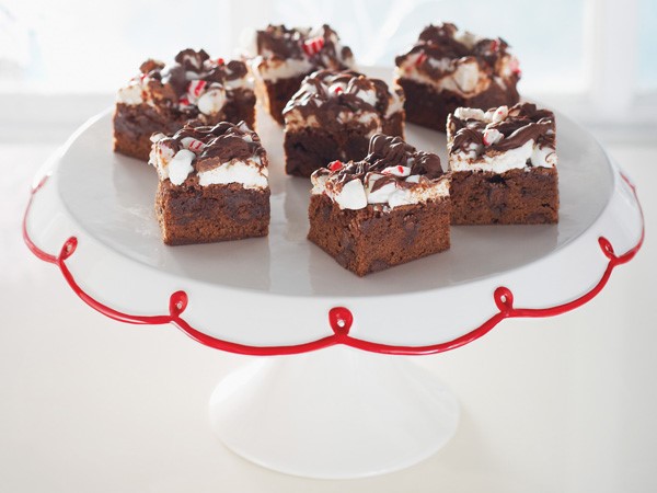 Chocolate chip brownie squares topped with mini marshmallows, crushed candy canes and drizzled melted semisweet chocolate chips on a white cake stand