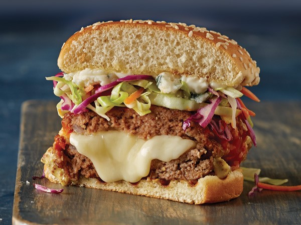 Burger stuffed with oozing cheese and topped with fresh vegetable tricolored slaw