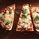 Italian bread slices topped with pizza sauce, melted mozzarella, black pepper and basil leaves