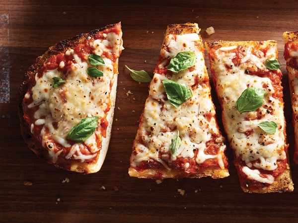 Italian bread slices topped with pizza sauce, melted mozzarella, black pepper and basil leaves