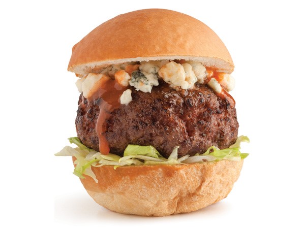 Grilled burger patty with lettuce, blue cheese crumbles and buffalo sauce sandwiched between a bun