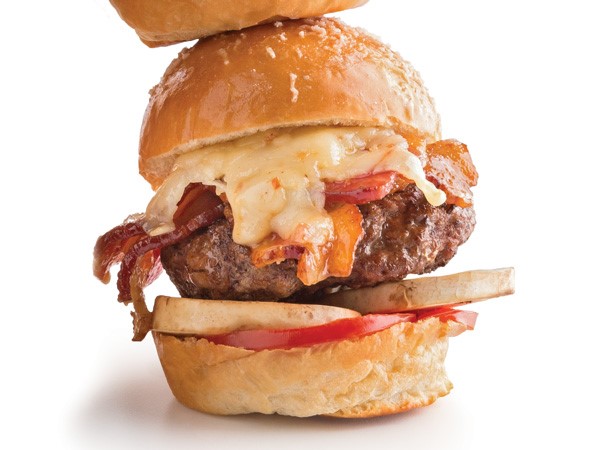 Burger patty with tomato, mushroom, bacon and cheese sandwiched betweeen a slider bun