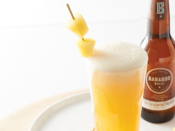 Glass of beer and bourbon cocktail with skewered pineapple chunks