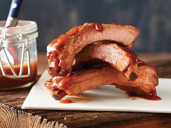 Stack of baby back ribs on a plate covered in Dr. Pepper BBQ sauce