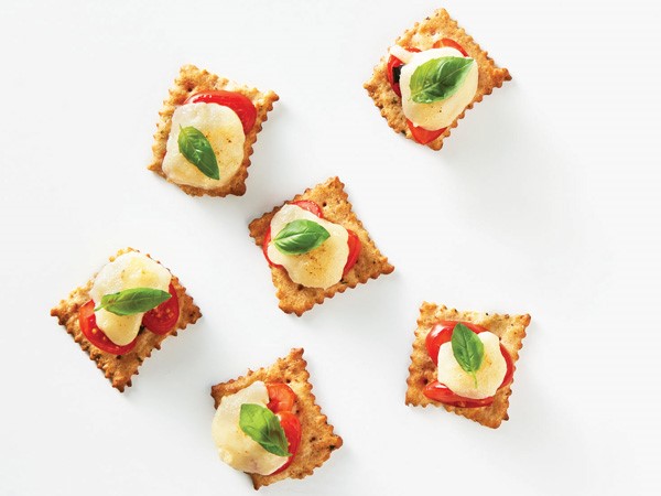 Crackers topped with tomato, mozzarella and basil