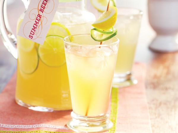 Pitcher and glass of summer beer, garnished with lime slice and lemon wedge