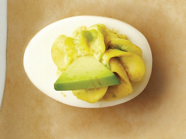 Deviled egg with avocado filling, garnished with an avocado slice