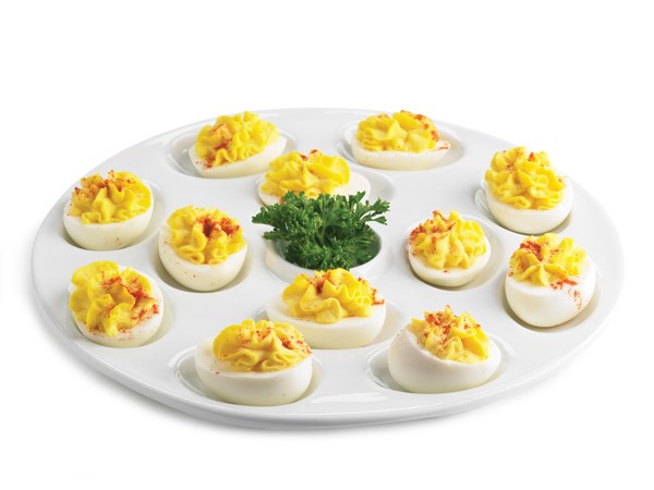 Deviled eggs on a white platter topped with paprika 