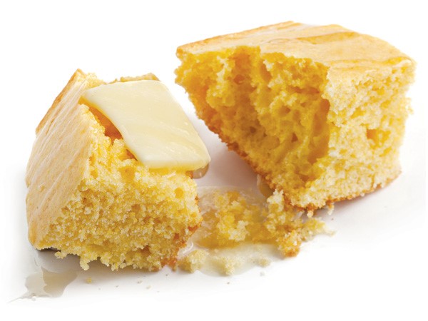 Piece of cornbread pulled apart with square of butter on top