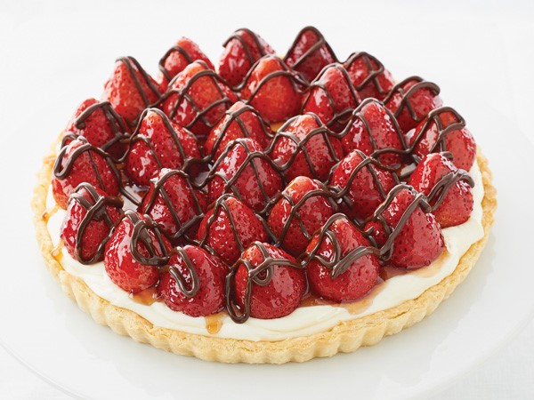 Tart topped with whole glazed strawberries drizzled with chocolate