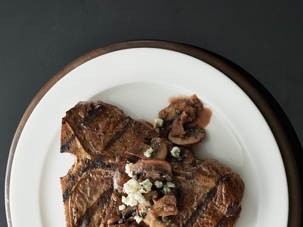 Grilled t-bone steaks topped with sauteed mushrooms and crumbled blue cheese