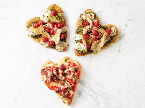 Three heart shaped pizzas with various toppings