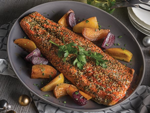 Pesto rubbed salmon on a large platter with roasted vegetables and garnished with parsley
