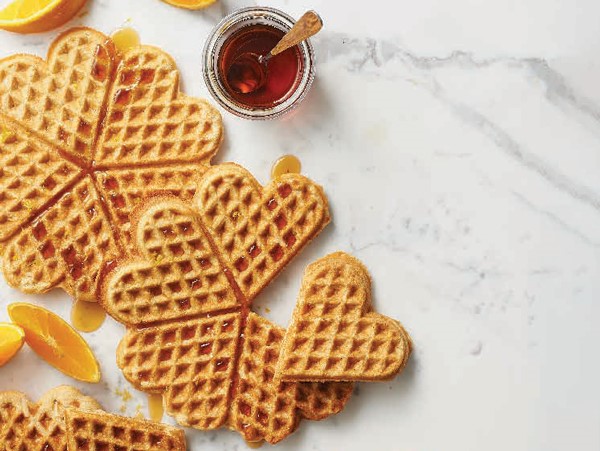 Heart-shaped almond-orange waffles topped with syrup