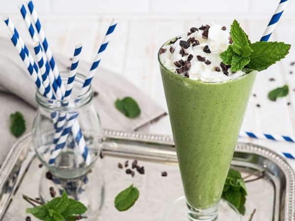 Green shake topped with whipped cream, mint, and chocolate chips