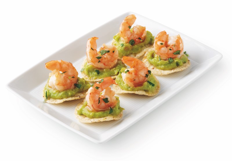 Platter of tortilla chips topped with guacamole and shrimp