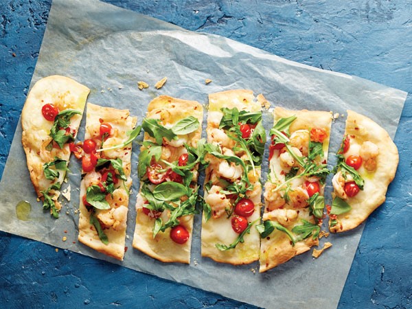 Crispy flatbread topped with greens, shrimp, tomatoes and cheese