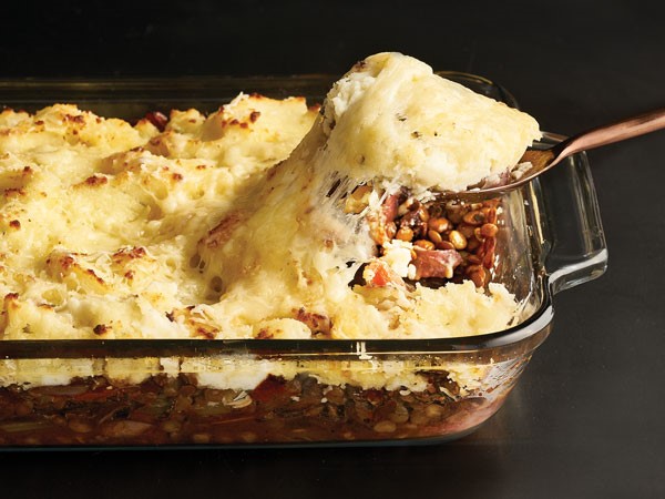 Casserole dish filled with shepherds pie with a serving spoon
