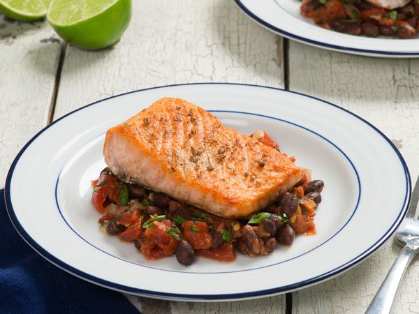 Cumin-seasoned salmon over black bean stew in a white bowl